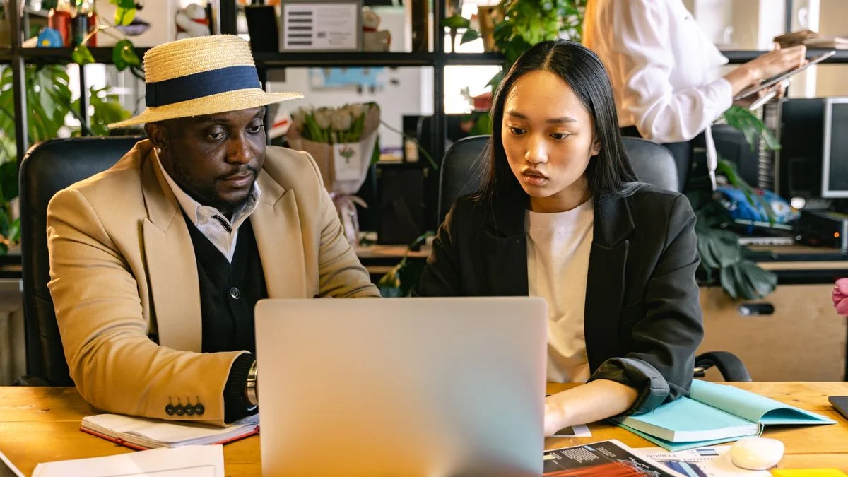 Equipe de colaboradores em treinamento prático no escritório usando notebooks para aprender a aplicar IA no trabalho