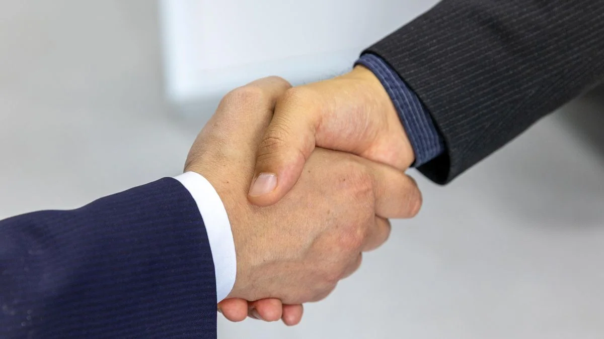 Aperto de mãos entre empresário e consultor de IA fechando parceria